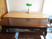 Overall view of light wood sofa table with lamp on top and dark wood coffee table in front