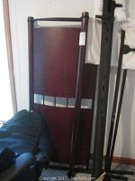 Full size bed headboard and footboard leaning against a wall, showing wood paneling and metal accents.