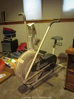 Full view of the DP Air Gometer DLX stationary bike showing seat, handles, fan wheel, and mechanical display.