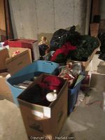 Bins and boxes filled with various Christmas decor items such as wreaths, stuffed toys, and other holiday decorations in a basement or storage area.