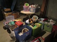 Overall collection of holiday decorations contained in plastic bins and cardboard boxes in a basement or storage area.