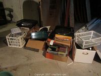Overall lot setup showing various boxes and crates containing a large collection of records and tapes stored on the floor in a basement or storage space.