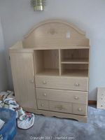 Front view of the particle board cabinet showing drawers, cupboard, shelving space, and floral decoration on the front panels.