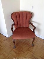 Front view of the vintage armchair showing rust upholstery and wooden legs