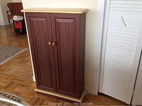 Front view of wooden shelf unit with two closed doors and wooden knobs.