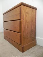 Side view showing three drawer dresser with wood veneer and rounded edges in medium brown color.