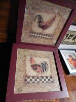 Two framed rooster prints with burgundy frames showing minor frame scratches, roosters standing on checkered pattern backgrounds.