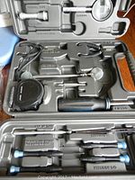 Tools and accessories organized in a black Sharper Image case with precision screwdrivers and tool extensions.