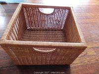 Medium size rectangular wicker basket with two handles, natural finish on wood floor.
