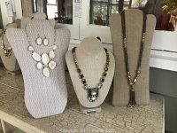Group shot of three gold-tone necklaces and one pair of matching earrings displayed on bust stands