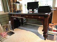 Front view of the desk showing glass top, drawers, legs and overall finish