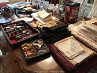 Wide shot of flatware, table linens, glassware, and other items arranged on dining table.