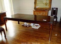 Full view of rectangular dining table with dark wood finish, extended design in place, showing sturdy legs and smooth top surface.