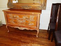 Front view of wooden chest of drawers featuring ornate carvings and distressed finish.