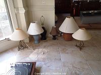 All seven lamps together on floor showing variety in heights and finishes