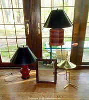 Three lamps and wooden framed mirror displayed together in front of glass doors, showing scale and condition