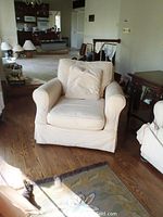 View of the upholstered armchair in a living room showing the front and side angled view.