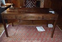 Full front view of the solid wood desk showing the decorative front panel and straight legs.