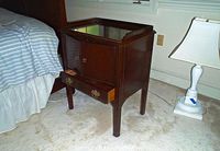 Full view of the Drexel Heritage wooden nightstand next to a bed and lamp, showing cabinet and drawer.