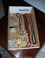 Overview of costume jewelry items, including necklaces, clip earrings, brooches, brass and glass trinket box, and Seiko watch.