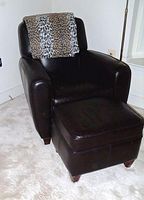 Leather armchair with matching ottoman in a room showing dimensions and overall condition.
