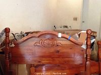 Front view of carved cherry wood headboard with shell and scroll engraving and turned posts