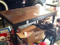 Top surface and partial side view of the Bassett dining table showing dark cherry wood top with wear and black painted legs and apron.