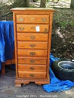 Full view of tall wood chest with 8 drawers and brass handles, showing overall condition and size.