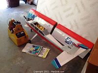 Overview of Easy 2 model airplane fuselage and detached wing sections, along with yellow power supply unit and manuals.