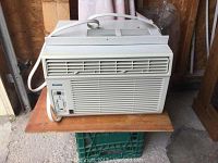 Front view of white Danby window air conditioner showing the front grilles, control panel and power cord coiled on side.