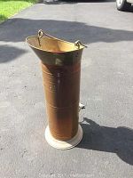 Full view of the vintage tall copper 5 Kan container with flared top and base, showing patina and wear.