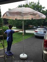 Photo of the patio umbrella open and standing outside with a person holding it to show scale.