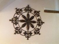 Front view of metal wall decor mounted on wall, showing overall design and size.