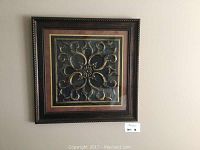 Full view of the framed square decorative wall artwork hanging against a wall.