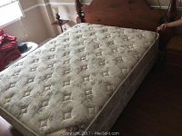 Full view of the queen size mattress on a wooden bed frame showing tufted floral upholstery