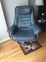 Front view of grey leather swivel recliner chair showing padded armrests and headrest pillow.