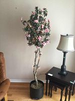 Full view of artificial flower tree showing height, pot, and string lights.