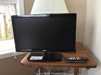 Front view of RCA 18-inch flat screen TV with remote placed on a wooden table.