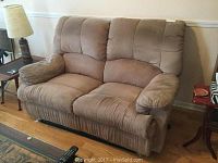 Full front view of the taupe faux suede love seat recliner showing overall condition and cushioning.