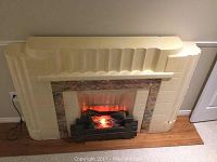 Full view of the cream formed fiberglass electric fireplace surround with electric firebox insert showing the design and condition including visible cracks.