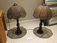 Pair of cane shade table lamps turned off showing detailed scalloped cane weave and dark wood turned base.