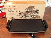 West Bend Automatic Electric Griddle laid out in front of its original box showing cooking surface and handles.