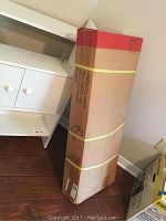 Photo of unopened tall box labeled Cambridge Steel Hammock, with end opened slightly to reveal taupe fabric color.