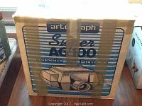 Original cardboard box for Artograph Super AG100 projector with taped top, displaying front artwork and model name.