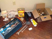 View of the blue toolbox with hand tools, Dial a Spray device, and other items spread on floor