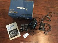 Sony Handycam Video8 CCD-TR4 camcorder with original box, two battery packs, charger, user manual, and power cables laid out on a wooden floor.