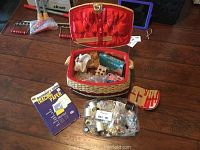 Full view of sewing basket with lid open showing sewing items inside and finished bag of assorted buttons and other notions in front
