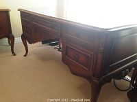 Front corner of desk showing drawer configuration and cabriole leg.