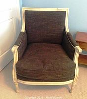 Front view of the armchair showing dark brown upholstery and distressed cream wood frame.