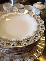 Stack of bone china dinner and dessert plates showing decorative brown floral borders